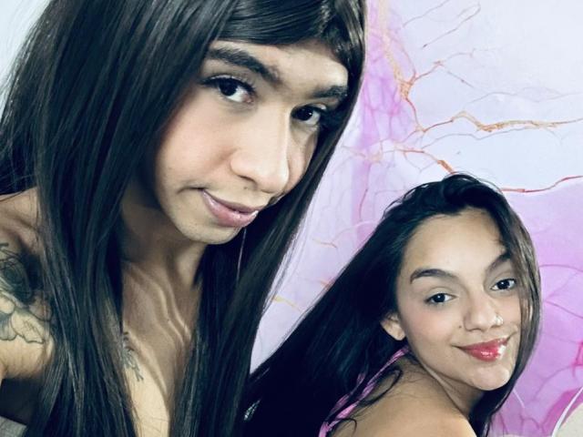 HailyAndAlisa, due donne latine con lunghi capelli neri, che mostrano i loro tatuaggi e sorridono, con HailyAndAlisa a sinistra e una versione più piccola, con un sorriso appena accennato, a destra..