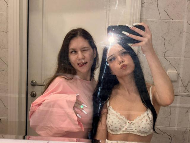 LornaAndGerry, con lunghi capelli castani e una camicia rosa, che fa l'occhiolino, accanto a LornaAndGerry con capelli neri, un reggiseno di pizzo bianco e labbra piene, che si scatta un selfie davanti a uno specchio del bagno..