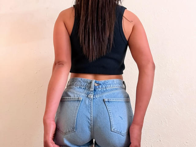 AlinaVale's ass in high-waisted, light blue jeans with visible pockets. She's wearing a black ribbed crop top, standing with her back to the camera.