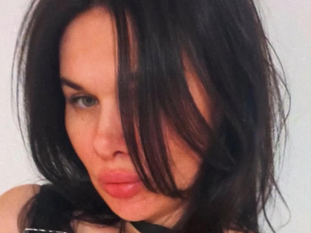 SophieVirginia, con i capelli neri, leggermente spettinati, che le coprono un occhio, labbra rosa e piene e un'espressione seria. Sta guardando direttamente la fotocamera, e il suo viso occupa gran parte dell'inquadratura..