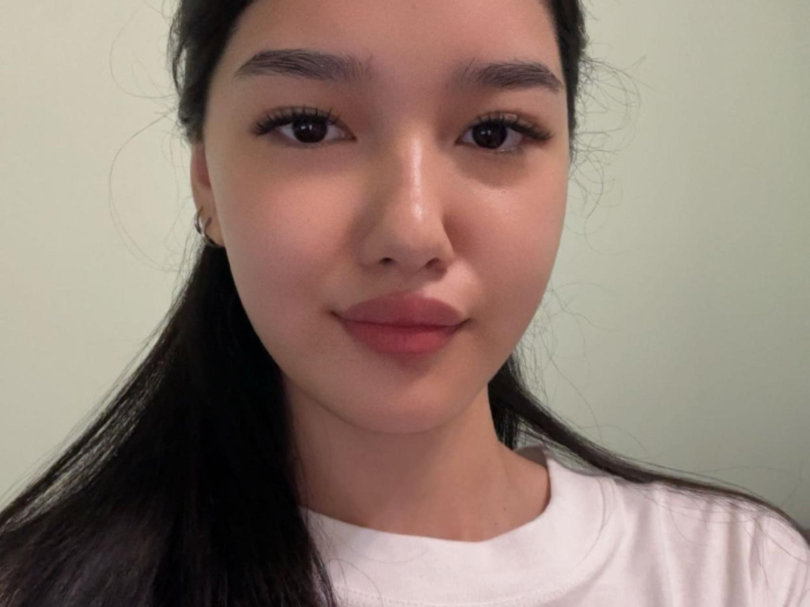 Un selfie de CourtneyLina con cabello largo y negro, vistiendo una camisa blanca, mirando directamente a la cámara con una sonrisa sutil, ojos marrones y piel clara..
