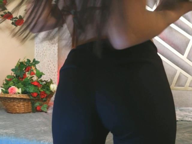 ChloeXk's black booty, tight as a drum, in black pants. Long brown hair, topless. Wicker basket with red roses and green leaves on the left.