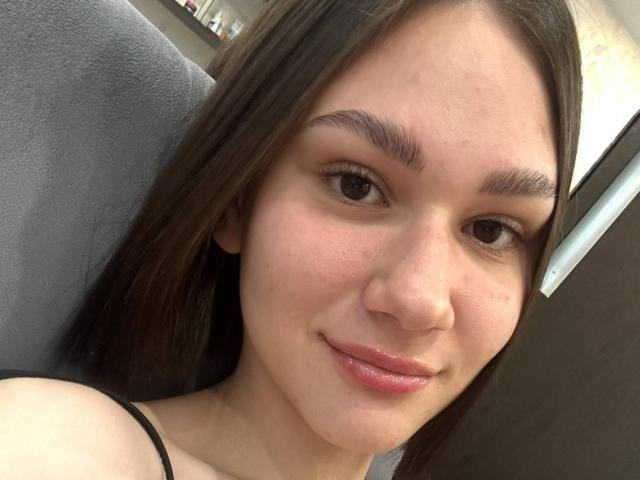 TobiQuinby ha la pelle chiara, gli occhi marroni e i capelli lunghi castani, con un leggero sorriso e labbra rosa. Ha sopracciglia piccole e scure e indossa un top nero a spalline..