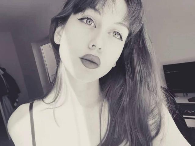 CarrieSorenson ha la pelle chiara, rossetto scuro e capelli lunghi e lisci con frangia, indossa un top nero con spalline, e guarda la fotocamera con gli occhi leggermente socchiusi..