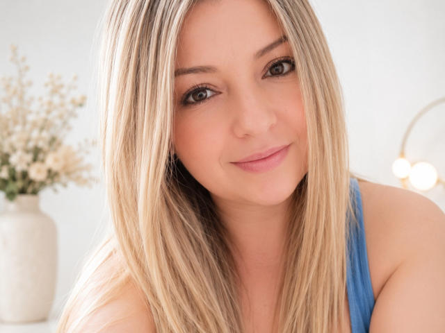 NatalyHami ha i capelli biondi, gli occhi azzurri e un leggero sorriso. Indossa una maglietta blu che lascia scoperte le spalle. Ha il seno piccolo e la pelle chiara..