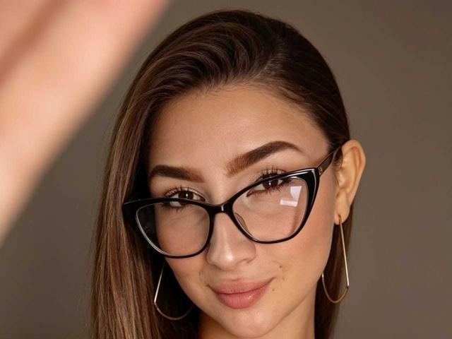 AbbyMilers tiene el pelo castaño, gafas negras y lleva pendientes de aro dorados. Está sonriendo con una ligera mueca, y su piel es clara. Sus senos no son visibles..