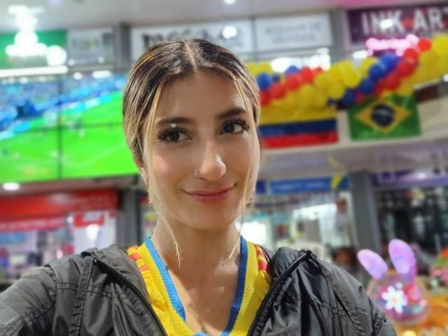 Kaiix tiene la piel de color marrón claro, ojos marrón oscuro y una pequeña sonrisa. Lleva una chaqueta negra con detalles amarillos y azules, y tiene un lanyard azul..