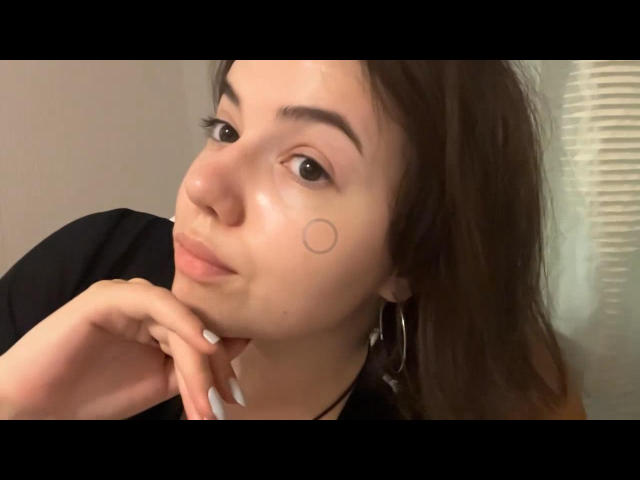 Elina Haycock ha la pelle chiara, gli occhi marroni e un piccolo tatuaggio a forma di cerchio sotto l'occhio destro. Ha un'espressione accigliata, con la mano vicino alla bocca, e indossa una maglietta nera..