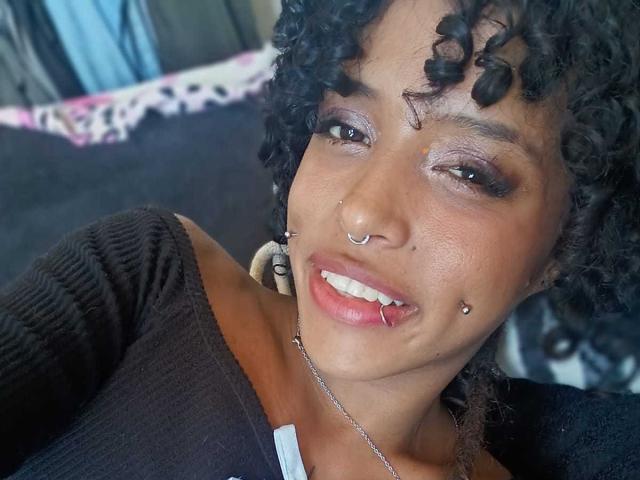 LunaKeller ha i capelli neri e ricci, gli occhi marroni e diversi piercing sul viso, tra cui un anello al naso e uno alle labbra. Sorride, con il rossetto rosa, e indossa una maglietta nera..