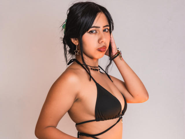 AyameFoxy com biquíni preto, mostrando seios pequenos, usando brincos de estrela, mão no cabelo, olhando para a câmera, pele clara, cabelo escuro, maquiagem discreta, pulseira, colar, sorriso leve, iluminação suave..