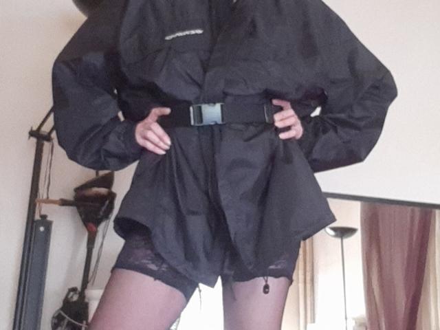 IssahneMay in a black, long-sleeve, oversized shirt with a belt, black lace stockings, standing with hands on hips, showing a small, barely visible, black lace pussy.