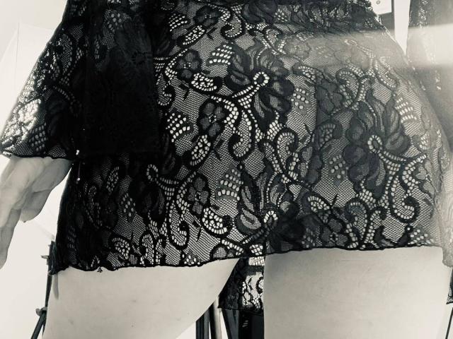 El trasero cubierto de encaje de Katarina Novak, con una parte superior de lencería negra, transparente y con estampado floral, que muestra sus muslos desnudos y blancos, y un ligue en el lado izquierdo. Foto en blanco y negro..