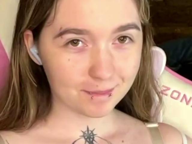 Liz Barrickman tem pele clara, olhos castanhos e cabelos longos castanhos. Ela tem um piercing no nariz, um piercing no lábio e uma tatuagem de estrela no peito. Ela está usando fones de ouvido brancos..
