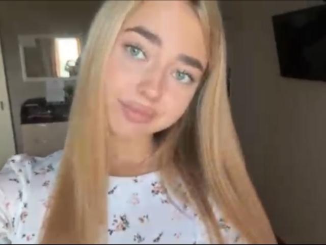 Georgine Branen, con cabello rubio, ojos verdes y piel clara, vestida con una camisa estampada con flores, sonriendo ligeramente, en un selfie con maquillaje discreto, luciendo linda y atractiva..