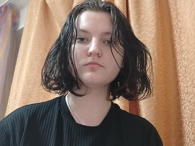 SandyBouley ha i capelli neri e umidi, lunghi fino alle spalle, la pelle pallida e un'espressione seria. Indossa una maglietta nera a coste. Il suo naso è leggermente all'insù..