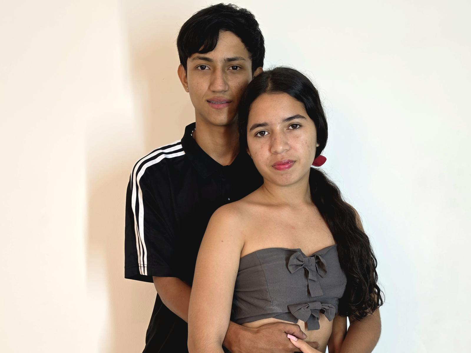 SofiaSteven, con cabello negro y aretes rojos, vestida con un top gris sin tirantes, de pie frente a SofiaSteven, con cabello negro, vestida con una camiseta deportiva negra, con los brazos alrededor de ella..
