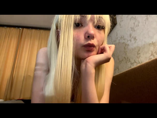 Shawanda Pershing mit blonden Zöpfen, Nasenring und heller Haut, die ihr Kinn in die Hand legt, in die Kamera blickt, ihre nackten Schultern zeigt und einen leicht schmollenden Gesichtsausdruck hat..