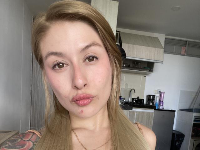 Isabella Palacio heeft lichtbruin haar, volle, roze lippen en een kleine puistje op haar kin. Ze draagt een mouwloos topje, waar een kleurrijke tatoeage op haar linkerarm zichtbaar is..