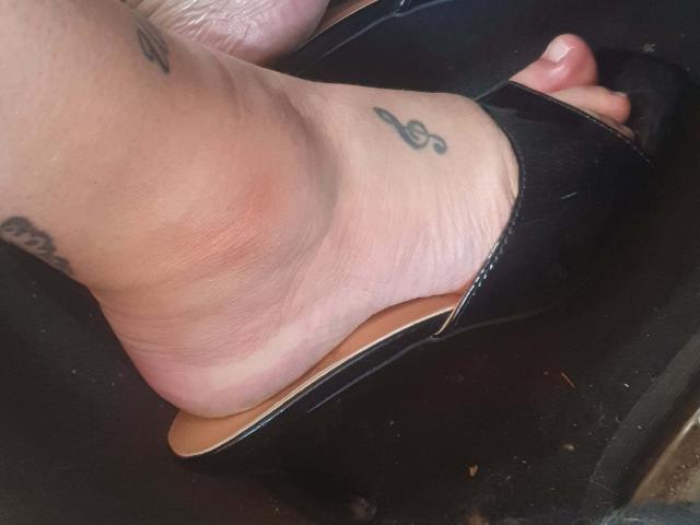 O pé de Choukette, com um salto preto, mostrando uma tatuagem de uma clave de sol no tornozelo e outra pequena tatuagem no calcanhar. Sua pele é levemente rosada..