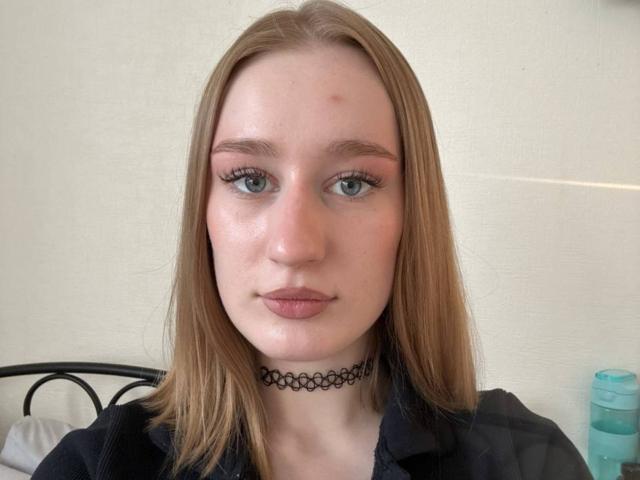 YettaMoulinos ha la pelle chiara, gli occhi azzurri e i capelli castano chiaro. Indossa un choker nero e una camicia scura. Ha una piccola macchia rossa sulla fronte..