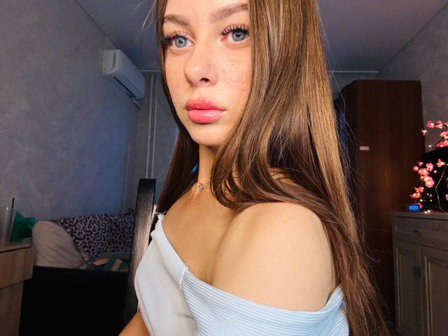 Kimberly Zampieri heeft lang bruin haar, blauwe ogen, roze lippen en een lichte huidskleur. Ze draagt een witte top met een open schouder, waardoor haar kleine borsten zichtbaar zijn, en een choker ketting..