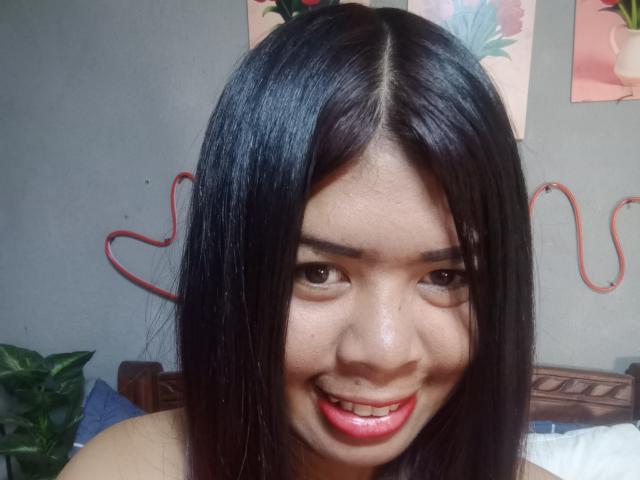 MariahSquirting69 ha i capelli neri e lisci, gli occhi marroni e un sorriso con le labbra rosse, con il naso visibile e un leggero trucco. È in un selfie, che mostra il suo viso e le spalle..