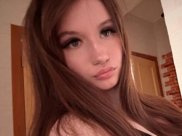 Latisha Streetman, com cabelos castanhos longos, olhos verdes e lábios rosados, vestindo uma blusa preta, exibe uma expressão sutil e sexy em uma selfie. Seus seios estão ligeiramente visíveis..