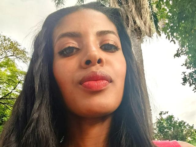 CamilaWest has dark brown hair, full red lips, and brown eyes with long eyelashes. She's looking at the camera with a neutral expression. Her nose is small and black.