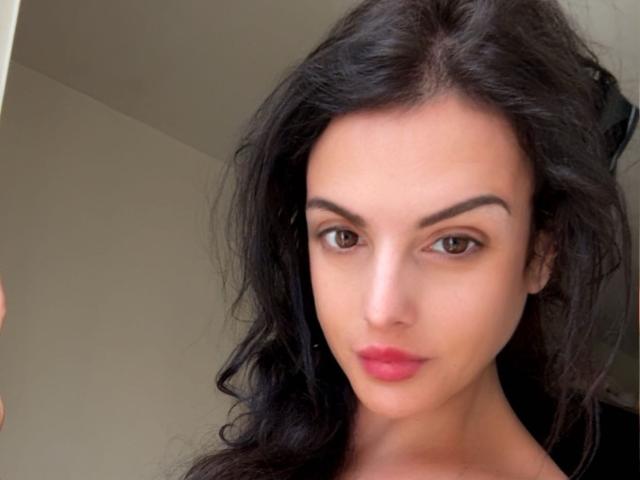 Sloaneswan tiene el cabello oscuro y ondulado, ojos marrones y lápiz labial rojo. Su rostro tiene una ligera inclinación, mostrando una expresión tranquila. Sus cejas son gruesas y bien definidas..