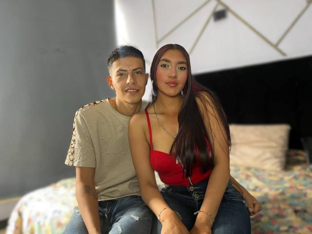Celeste und Blake, Celeste mit langem, braunen Haar in einem roten Oberteil und blauen Jeans, sitzen neben Blake mit kurzem, schwarzem Haar in einem beigen Hemd, auf einem Bett..