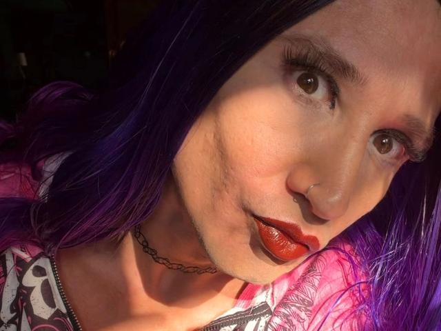 MaryXXL-hot with purple hair, brown eyes, red lips, nose ring, choker, and patterned top, sunlight on her face, slight shadow on her cheek, showing her sexy look.