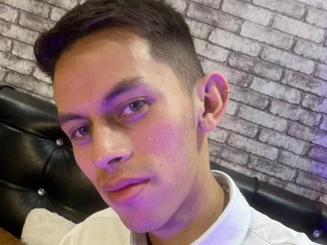 AnderCooper hat kurze, dunkle Haare, einen leichten Schnurrbart und ein weißes Hemd. Er blickt neutral in die Kamera, seine Nase und Ohren sind sichtbar..