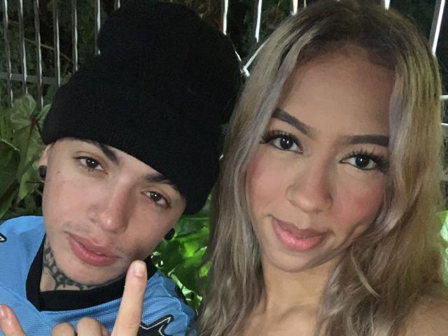 NickySixNine, com cabelo castanho claro e olhos escuros, sorrindo, ao lado de NickySixNine usando um gorro preto, mostrando o sinal da paz, vestindo uma camisa azul. Ambos têm tatuagens..