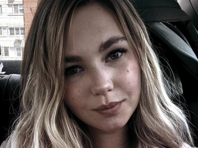 LawandaMuzzy has blonde wavy hair, green eyes, and a subtle pout with light pink lipstick. She's sitting in a car, looking slightly to the side with a relaxed expression.