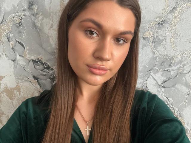 Lakeisha Cresencio tiene el cabello castaño lacio, piel morena y labios rosados y gruesos. Lleva una blusa verde de terciopelo con un collar de cruz dorado. Sus ojos son marrones y está mirando a la cámara..
