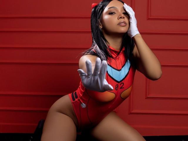 NashaLoule in a red, tight, heart-cutout bodysuit, white gloves, and red headband, reaching out, with her hand on her head, showing her tits and ass.