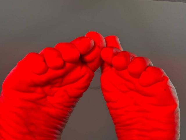 LilithRussoo's red-painted feet with toes slightly curled, showing wrinkled soles and textured skin. She's touching the tips of her toes together.