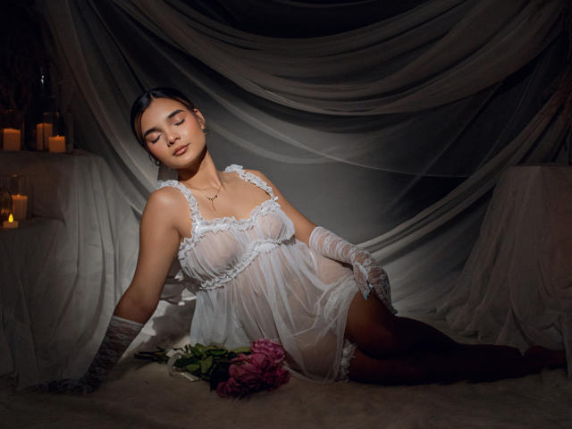 IvannaHazel, mujer asiática, vestida con lencería blanca de encaje transparente, guantes a rayas, ojos cerrados, acostada, rosas rosadas, habitación oscura, velas, iluminación suave, vestido semitransparente, sexy, relajada..
