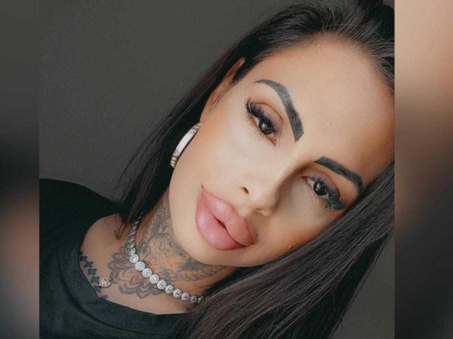 DenyChantal ha il collo tatuato, labbra piene e sopracciglia scure. Indossa una maglia nera e orecchini di diamanti. I suoi lunghi capelli neri sono pettinati all'indietro..