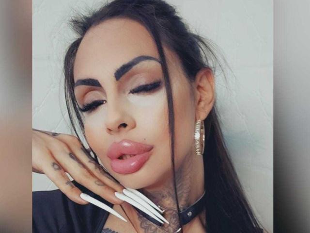 DenyChantal ha i capelli scuri, sopracciglia folte, unghie lunghe e bianche, labbra rosa lucide, una collana nera e orecchini dorati. Ha un tatuaggio sul collo, gli occhi chiusi e le labbra leggermente dischiuse..