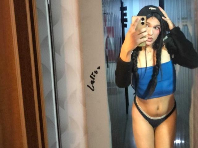 PamelaXFox with long black braids, blue tube top, black panties, and black hoodie, taking a mirror selfie, showing her flat stomach and small tits.