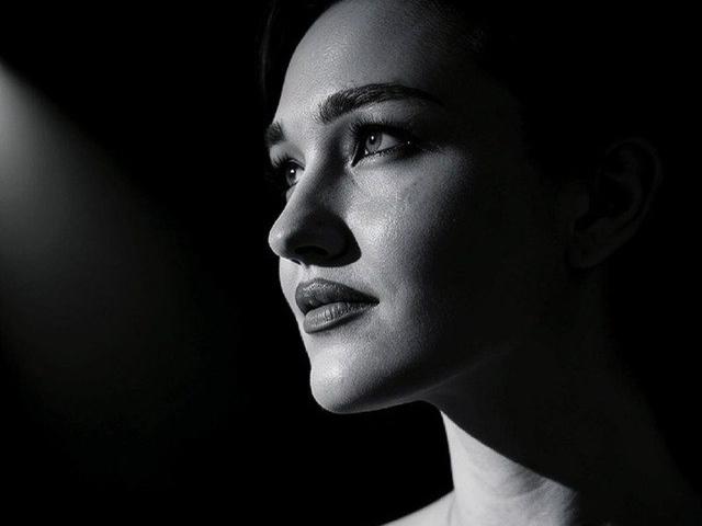 Black and white photo of DorianCieslinski's face, illuminated from the left, showing a smooth, shiny complexion, arched eyebrows, and subtle smile, with a focused, gentle expression.