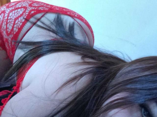 Le soutien-gorge et la culotte en dentelle rouge de LucieCurie, qui montrent ses fesses et son dos, avec de longs cheveux bruns qui lui couvrent le visage, allongée. Sa peau pâle est visible..