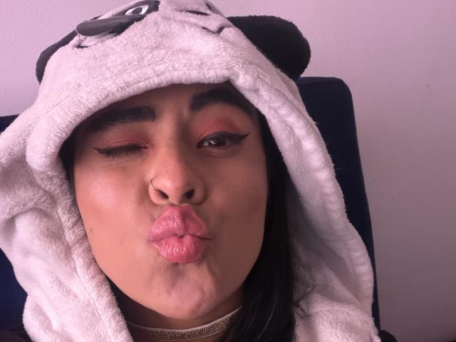 StellaBeckker with puffy pink lips, wearing a white panda hoodie, has a nose ring, and half-closed eyes with pink eyeliner, looking cute and playful.