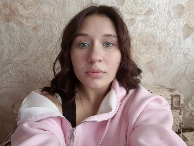 LinseyMayhan hat blaue Augen, helle Haut und welliges braunes Haar. Sie trägt eine pinke Jacke mit Reißverschluss und weißem Innenfutter und schaut direkt in die Kamera..
