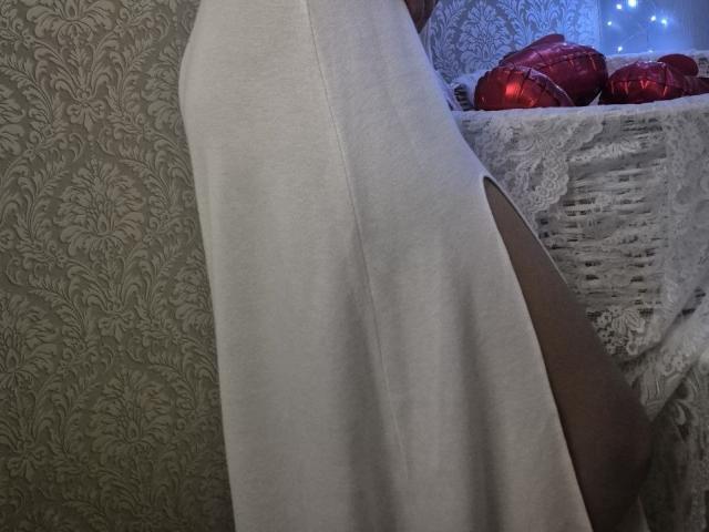 Anshante's white dress has a side slit, showing her bare thigh and butt. Red heart-shaped decorations are on a lace-covered table.