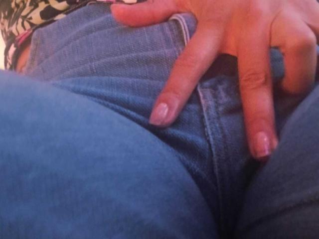 ZarayFeet's hand with pink nail polish rests on their blue jeans, fingers pulling down the waistband to expose a hint of their pussy.
