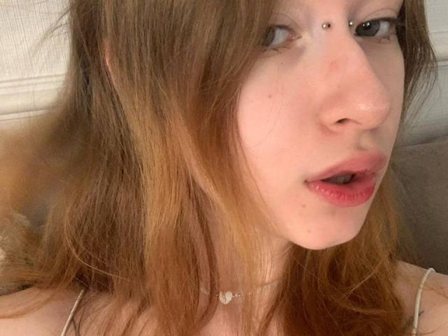 MaritaPavelko's face with light skin, brown wavy hair, nose piercing, and pink lips, wearing a thin choker, showing her slightly open mouth. Her tits are not visible.