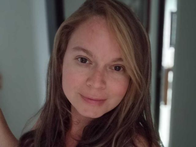 PamelaColin with brown hair, a small nose, and a subtle smile, has a cute face and a small, unobtrusive ass, looking directly at the camera.