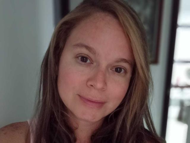 PamelaColin has light brown hair, brown eyes, and a slight smile. She's looking at the camera with a relaxed, natural expression. Her face is slightly freckled.